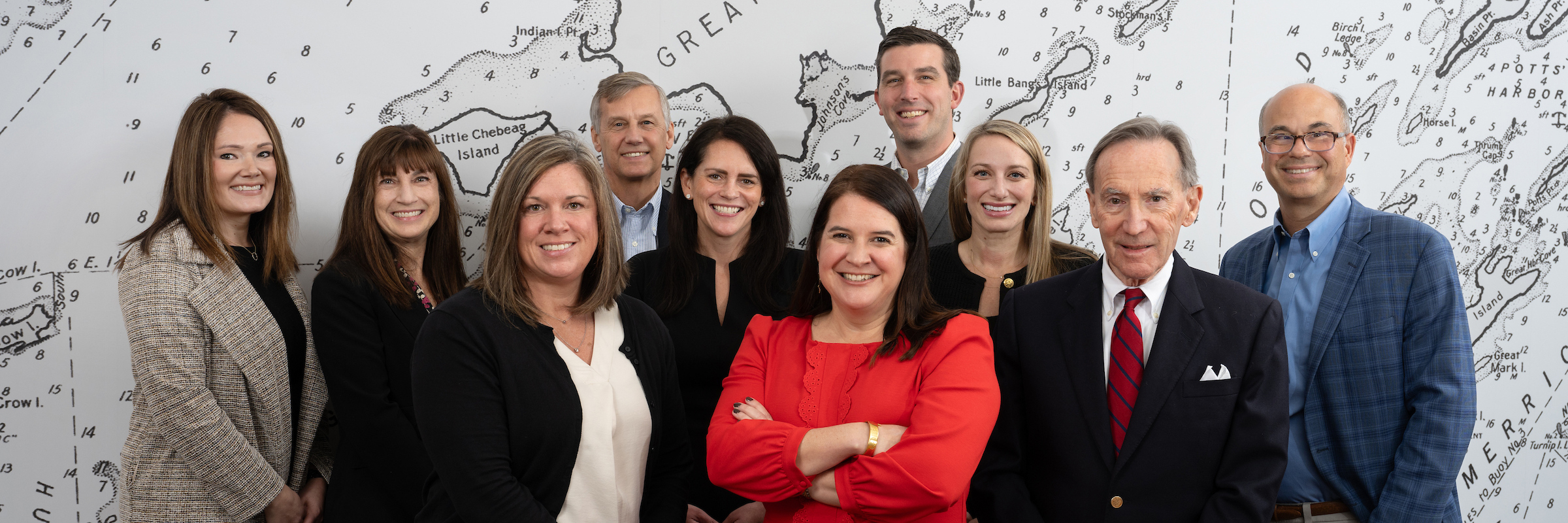 The Spinnaker Trust team standing in front of a decorative map wall in their office